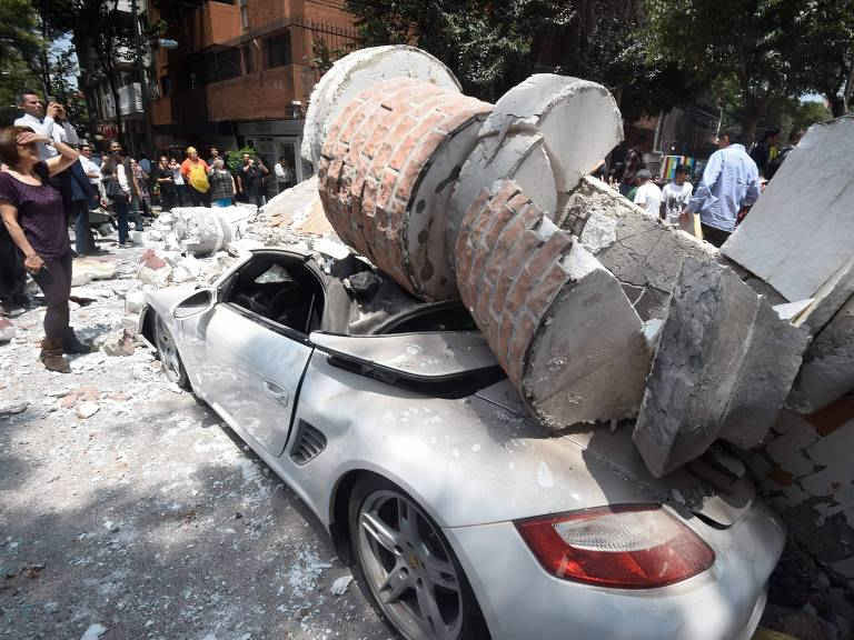 Xe ô-tô bị mảnh vỡ của tòa nhà đè bẹp. (Ảnh: Getty Images)