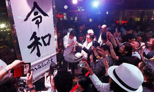 Người dân Nhật chụp tên triều đại Reiwa (Lệnh Hòa) trong sự kiện đếm ngược chào mừng tân Nhật hoàng và triều đại mới đêm 30/4 ở Tokyo. Ảnh: AP.